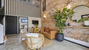 a living room with a couch and a brick wall at Catalyst Retreat - Stylish, Pets, Accessible, Sauna in Coffs Harbour