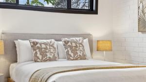 a bedroom with a bed with pillows and two lamps at Catalyst Retreat - Stylish, Pets, Accessible, Sauna in Coffs Harbour