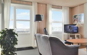 a living room with a chair and a table and windows at Three-Bedroom Holiday Home In Hvide Sande in Havrvig +17 photos