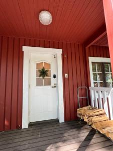 a red house with a white door on a porch at Second House sch-sch(スクスク） in Kita-karuizawa