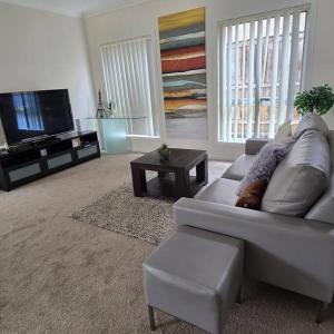 a living room with a couch and a flat screen tv at Cosy 5 x bedroom Kellyvil Ridge in Kellyville