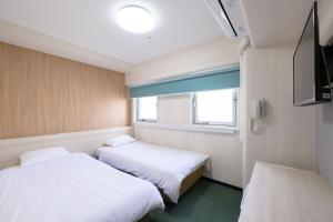 zwei Betten in einem kleinen Zimmer mit Fenster in der Unterkunft Hotel Kansai in Osaka