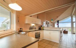 a kitchen with white cabinets and a large window at Holiday Home Godthåbsvej Rømø Vi in Bolilmark