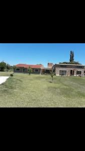 un gran edificio con un campo de césped delante de él en El Ceibo, en Villa Las Rosas