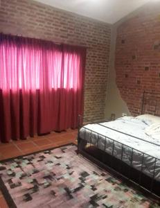 Un dormitorio con una cama y una cortina roja. en El Ceibo, en Villa Las Rosas