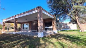 a brick house in a park with a tree at Casa de verano confortable in Villa Las Rosas