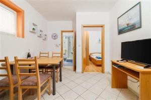 a kitchen and dining room with a table and a television at Apartman Julija in Povile
