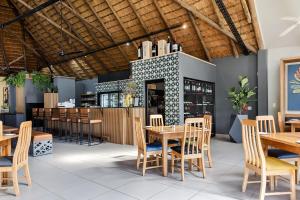 a restaurant with wooden tables and chairs and a bar at Hippo Hollow Country Estate in Hazyview
