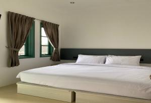 ein Schlafzimmer mit einem großen weißen Bett mit einem Fenster in der Unterkunft Binumar Guest House in Pekalongan