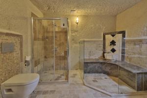 a bathroom with a toilet and a glass shower at Jacob's Cave Suites - Cappadocia in Goreme