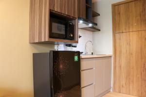 ブカシにあるSimply Look Studio Room Gateway Park LRT City Jatibening Apartment By Travelioの黒い冷蔵庫と電子レンジのあるキッチン