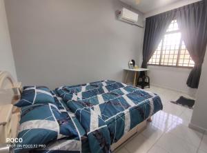 a bedroom with a bed with a blue comforter and a window at 55 Homestay Bakri Muar Lovely House 12 pax in Kampong Parit Ulu