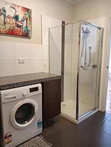 a washing machine in a bathroom with a shower at Coastal Comforts in Aspendale +12 photos