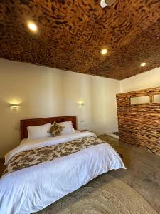 a bedroom with a large bed with a wooden ceiling at Palm Cultural Village in Paje