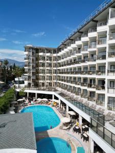 a large apartment building with a swimming pool and patio at Monte Carlo Hotel in Alanya