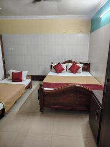 蓬蒂切里Malar Residencee的一间卧室配有两张带红色枕头的床