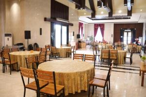 una sala banchetti con tavoli e sedie e una stanza con una stanza per non essere stata organizzata di Thong's Inn Hotel Kualanamu a Medan
