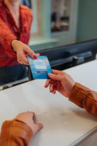 a woman is handing a person a blue card at Kyriad Cannes - Mandelieu in Cannes