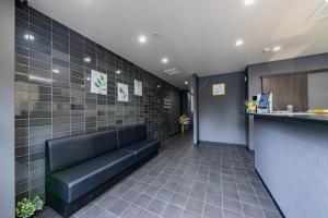 a waiting room with a black leather couch in a building at JA Hotel Shinfukae in Osaka