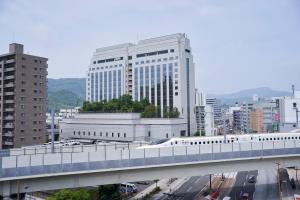 Un tren en un puente en una ciudad con edificios. en THE GLOBAL VIEW Nagasaki, en Nagasaki