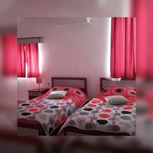 Morović的住宿－維拉諾瓦旅館，卧室内的两张床,配有红色窗帘和红色窗帘