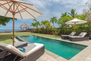 una piscina con sillas y sombrilla en Villa Emerald, en Banjar