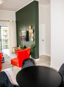 - un salon avec une table noire et des chaises rouges dans l'établissement Modern Retreat in Pretoria with Lagoon Pool & Gym, à Pretoria