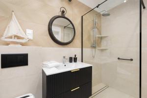 Un baño con lavabo y ducha con espejo. en Prestiżowy Apartament Baltic Sand 300 m od Plaży Mrzeżyno by Noclegi Renters, en Mrzeżyno