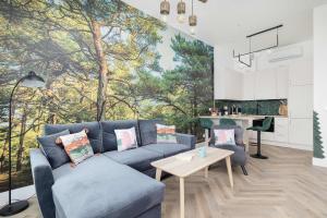 Una sala de estar con un sofá azul y una cocina. en Prestiżowy Apartament Baltic Sand 300 m od Plaży Mrzeżyno by Noclegi Renters, en Mrzeżyno 33 fotos más