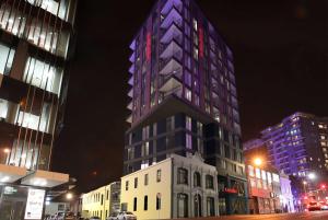 オークランドにあるRamada Suites By Wyndham Victoria Street Westの高い建物は夜にライトアップされる