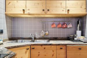 eine Küche mit Spüle und Holzschränken in der Unterkunft L'appartamentino del cuore in Bormio + 39 Fotos