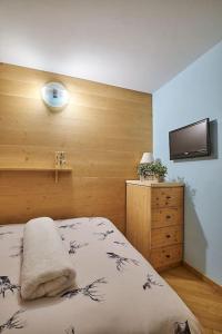 ein Schlafzimmer mit einem Bett und einem Fernseher an der Wand in der Unterkunft L'appartamentino del cuore in Bormio