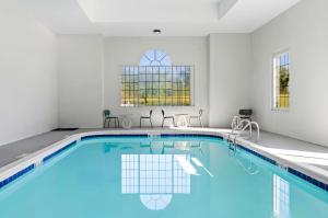 a swimming pool with blue water in a white room at Spark by Hilton Winston-Salem University in Winston-Salem