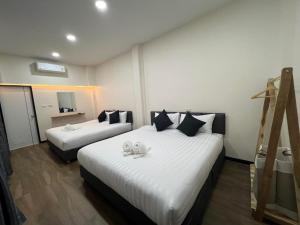 ein Hotelzimmer mit zwei Betten mit weißen Laken in der Unterkunft Carina PoolVilla Khanom คารีน่าพูลวิลล่า in Ban Phang Phrao + 5 Fotos