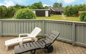 two white chairs sitting on a porch with a playground at Holiday Home Marie Nielsens Vej Glesborg Denm in Fjellerup Strand