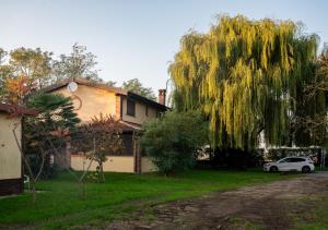 a white car parked in front of a house with a willow tree at Agri Village Pavia in Certosa di Pavia