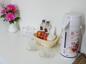 a table with glasses and a coffee maker and a basket of drinks at The SR Residence Lampang in Lampang