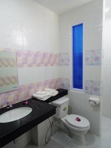 a bathroom with a toilet, sink, and mirror at The SR Residence Lampang in Lampang