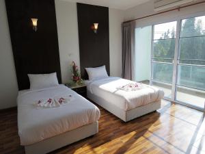 a hotel room with two beds and a window at The SR Residence Lampang in Lampang