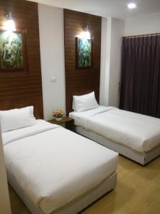 2 bedden in een hotelkamer met witte lakens bij The SR Residence Lampang in Lampang