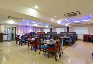 a restaurant with tables and chairs in a room at Akshaya Aura in Bangalore