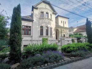 a white house with a fence and some plants at Kúria Apartman Private Wellness in Budapest