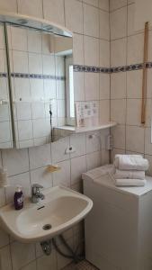 une salle de bains blanche avec un lavabo et un miroir dans l'établissement Ferienhaus Norddeich 27, à Norden