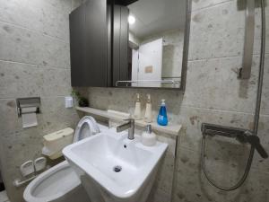 Un baño con lavabo, inodoro y espejo. en Present In Suseo, en Seúl 73 fotos más