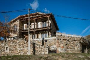 ein altes Steinhaus mit Balkon auf einem Hügel in der Unterkunft El Casuco in Santa María de Redondo