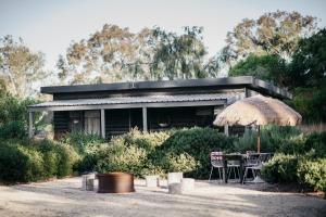 a house with a table and chairs and an umbrella at Esperance Chalet Village in Esperance
