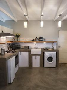 a kitchen with a sink and a washing machine at Blouberg Rise Cottage in Cape Town