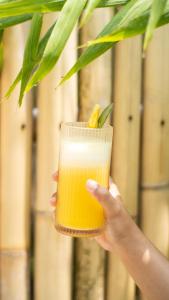 une personne tenant un verre de jus d'orange dans l'établissement The White Bay Lombok, à Kuta Lombok