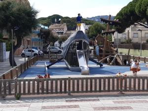 un parque infantil con un tobogán y una persona de pie en la parte superior en Perla del Mar, en Platja d'Aro