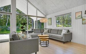 a living room with couches and a table and windows at Beautiful Home In Væggerløse With Sauna in Marielyst